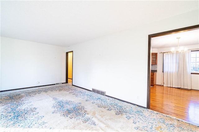 empty room featuring a chandelier and hardwood / wood-style flooring