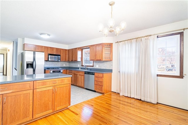 kitchen featuring tasteful backsplash, light hardwood / wood-style flooring, a healthy amount of sunlight, and appliances with stainless steel finishes