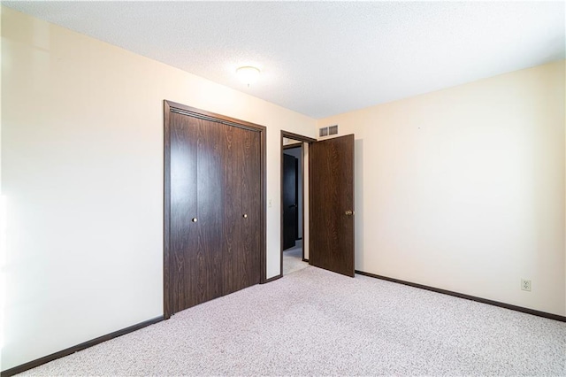 unfurnished bedroom featuring a closet, light colored carpet, and a textured ceiling