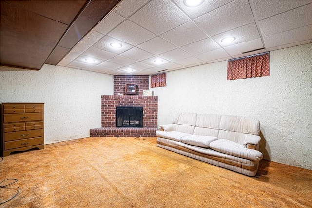 living room with a drop ceiling, carpet floors, and a brick fireplace