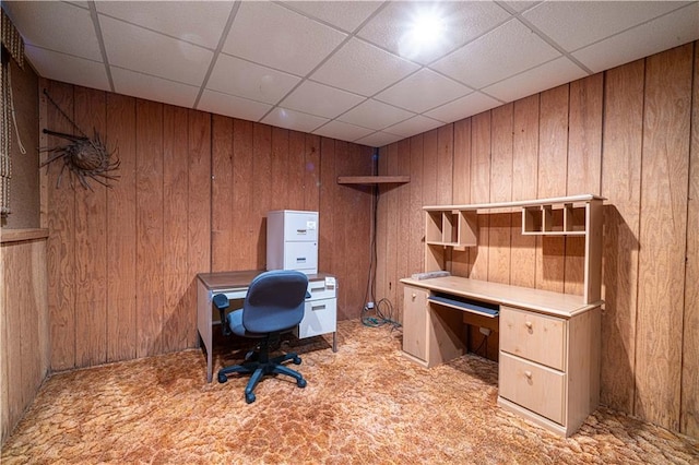 carpeted office space with a drop ceiling and wooden walls