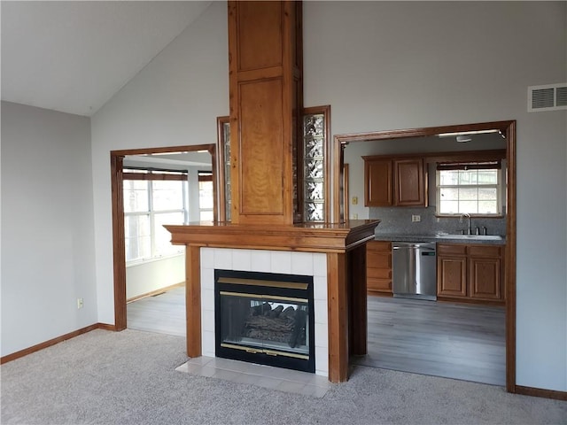 interior space with dishwasher, high vaulted ceiling, light wood-type flooring, and sink