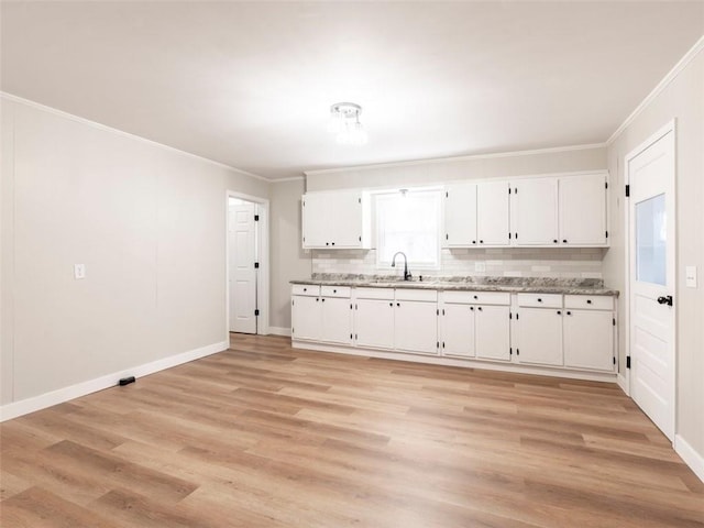 kitchen featuring sink, tasteful backsplash, crown molding, light hardwood / wood-style floors, and white cabinets