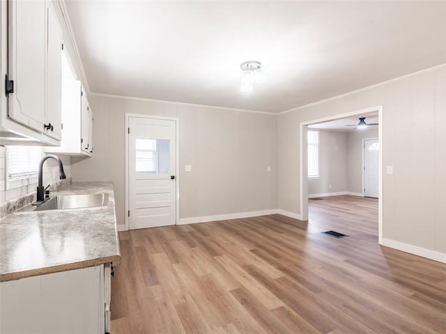 kitchen with a wealth of natural light, white cabinetry, sink, and light hardwood / wood-style floors