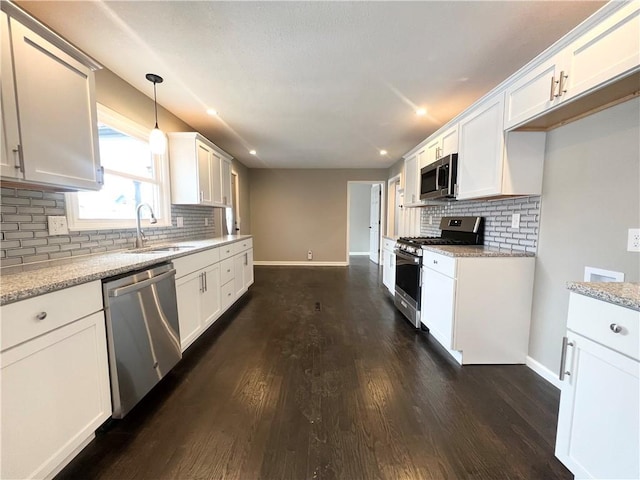 kitchen featuring dark hardwood / wood-style flooring, light stone counters, hanging light fixtures, and appliances with stainless steel finishes