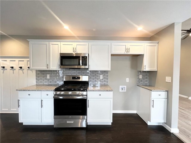 kitchen with white cabinets, light stone counters, and stainless steel appliances