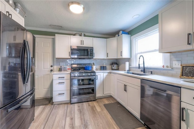 kitchen with sink, white cabinets, light wood-type flooring, and appliances with stainless steel finishes