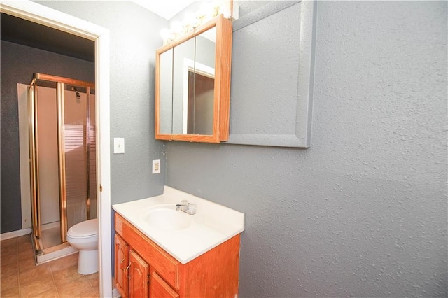 bathroom featuring tile patterned floors, a shower with door, vanity, and toilet