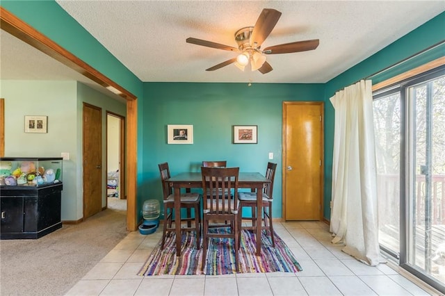 dining space with ceiling fan, light colored carpet, and a textured ceiling