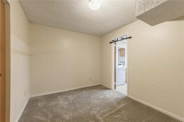 carpeted empty room featuring washer / clothes dryer and a textured ceiling