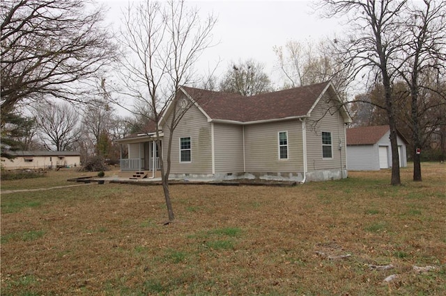 view of home's exterior featuring a lawn, an outbuilding, a porch, and a garage