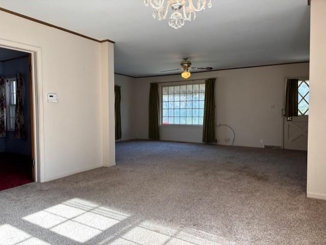 carpeted spare room featuring ceiling fan with notable chandelier