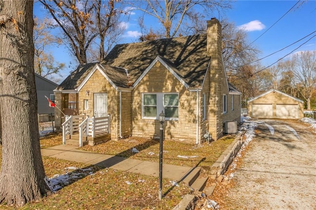 view of front of home with a garage, an outbuilding, and central AC