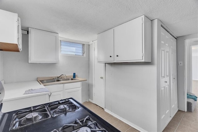 kitchen with a textured ceiling, white cabinetry, and sink