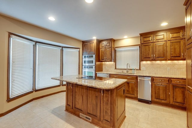 kitchen with decorative backsplash, appliances with stainless steel finishes, a center island, and sink