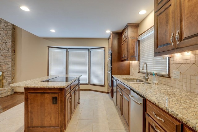 kitchen featuring dishwasher, sink, light stone countertops, black electric cooktop, and a kitchen island