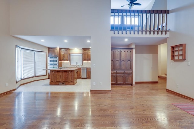 unfurnished living room featuring a wealth of natural light, light wood-type flooring, and a high ceiling