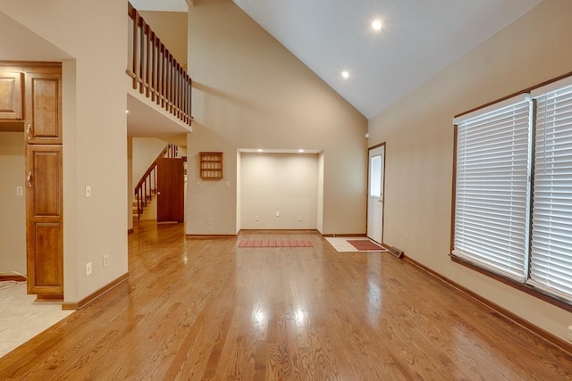 unfurnished living room with high vaulted ceiling and light hardwood / wood-style flooring