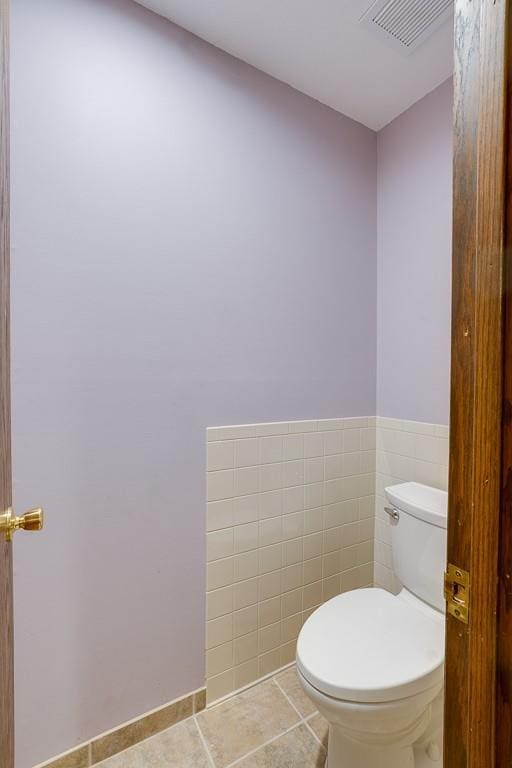 bathroom with tile patterned flooring, tile walls, and toilet