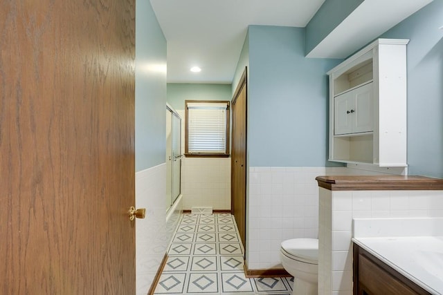 bathroom featuring tile patterned flooring, a shower, toilet, vanity, and tile walls