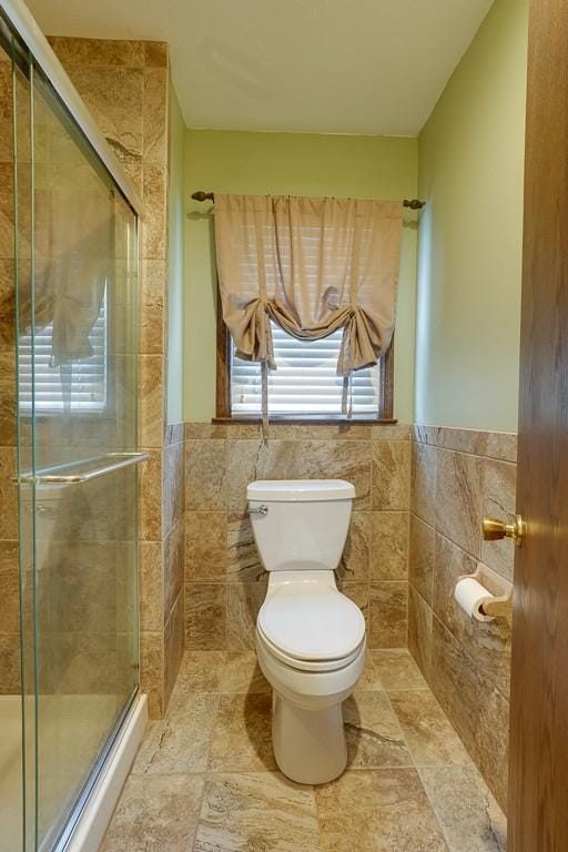 bathroom featuring toilet, tile walls, and walk in shower