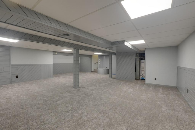 basement featuring gas water heater, a paneled ceiling, and light colored carpet