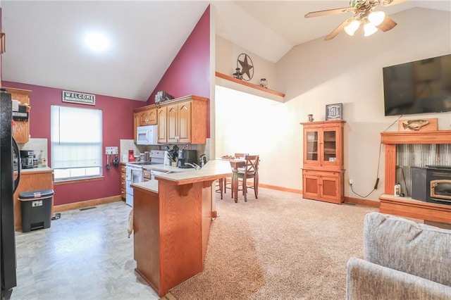 kitchen with white appliances, vaulted ceiling, ceiling fan, a kitchen bar, and kitchen peninsula