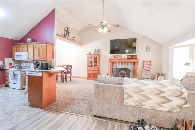 living room with a wood stove, light hardwood / wood-style flooring, vaulted ceiling, and ceiling fan