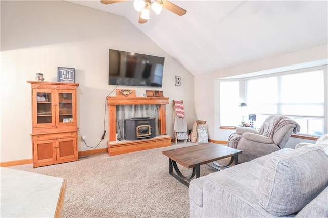 carpeted living room with plenty of natural light, ceiling fan, a wood stove, and vaulted ceiling