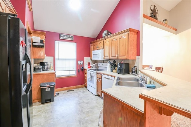 kitchen with vaulted ceiling, sink, a kitchen bar, and white appliances