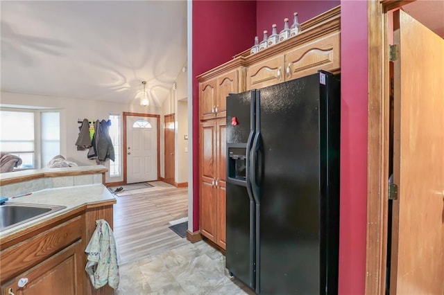 kitchen featuring sink, black refrigerator with ice dispenser, and light hardwood / wood-style flooring