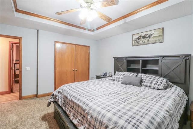 carpeted bedroom featuring a closet, a tray ceiling, and ceiling fan