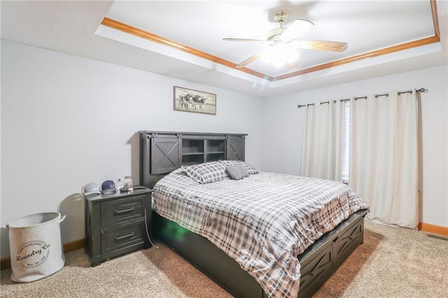 carpeted bedroom featuring ceiling fan, ornamental molding, and a tray ceiling