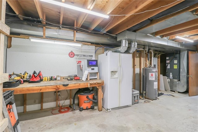 basement with a workshop area, water heater, heating unit, and white refrigerator with ice dispenser