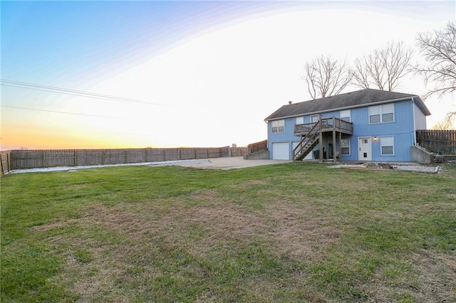 yard at dusk with a deck and a garage