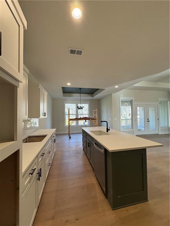 kitchen featuring sink, white cabinetry, an island with sink, and hanging light fixtures