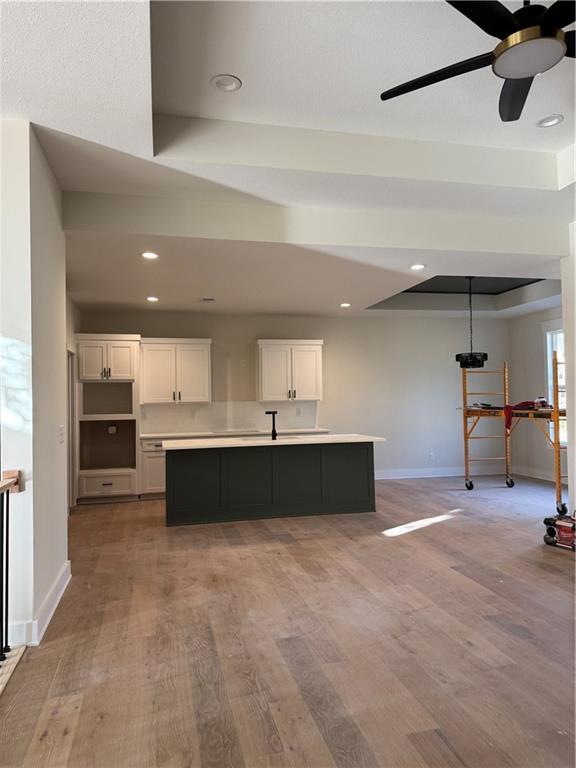 kitchen featuring white cabinets, ceiling fan, light hardwood / wood-style floors, and a center island with sink