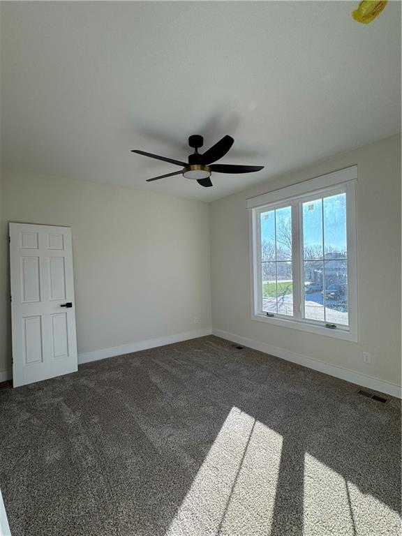 spare room with dark carpet and ceiling fan