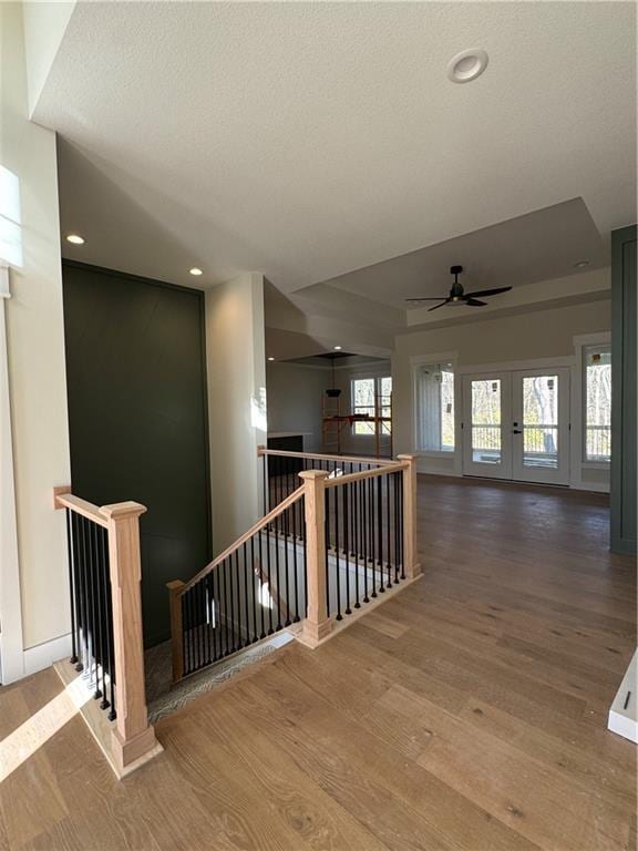 hallway featuring hardwood / wood-style floors, a textured ceiling, and french doors