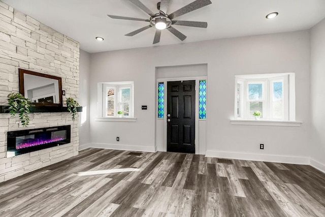 entrance foyer featuring dark hardwood / wood-style floors, ceiling fan, and a fireplace