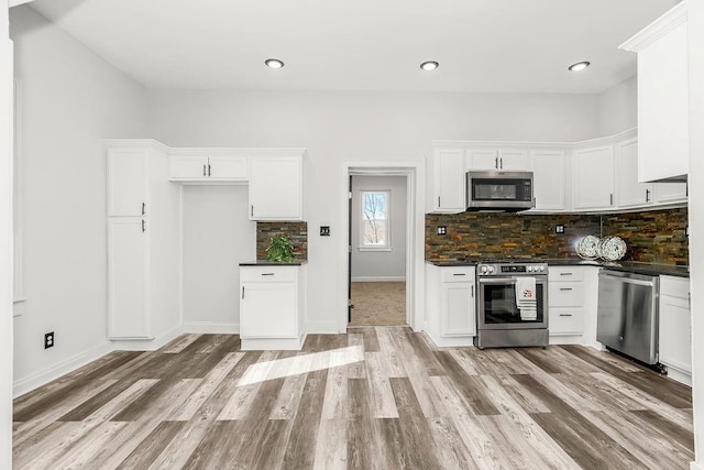 kitchen featuring backsplash, white cabinetry, stainless steel appliances, and light hardwood / wood-style flooring