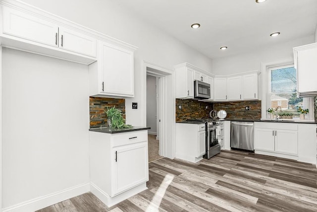 kitchen with decorative backsplash, appliances with stainless steel finishes, sink, wood-type flooring, and white cabinets