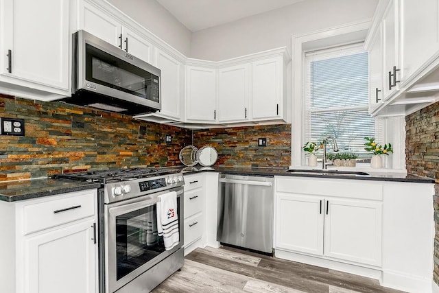 kitchen featuring decorative backsplash, stainless steel appliances, sink, light hardwood / wood-style flooring, and white cabinets