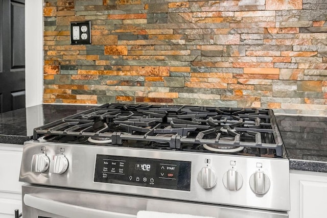 interior details with tasteful backsplash, white cabinetry, dark stone counters, and stainless steel range with gas stovetop