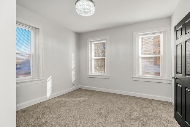 carpeted empty room with an inviting chandelier