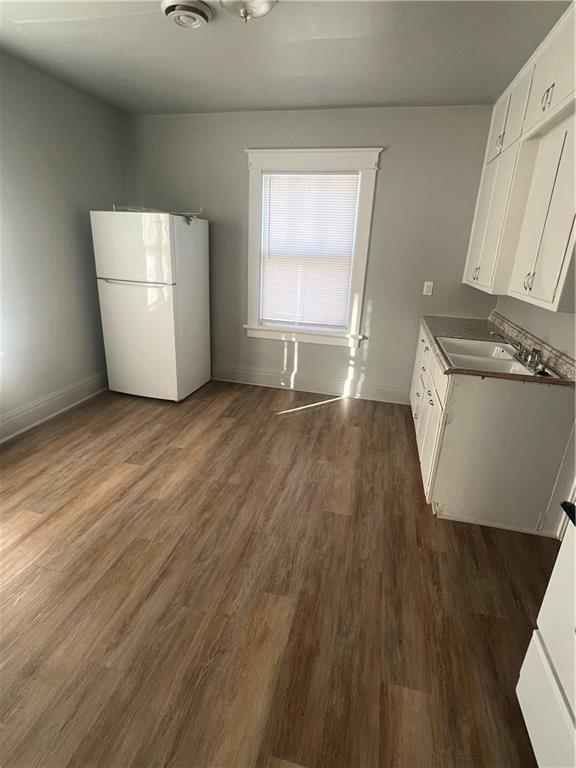 kitchen featuring dark hardwood / wood-style flooring, white cabinetry, sink, and white fridge