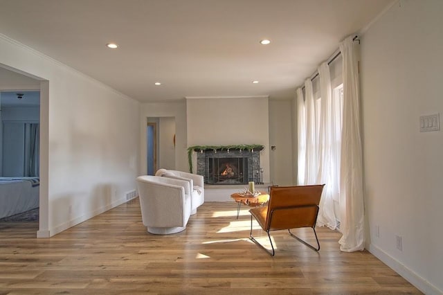 sitting room featuring ornamental molding and light wood-type flooring