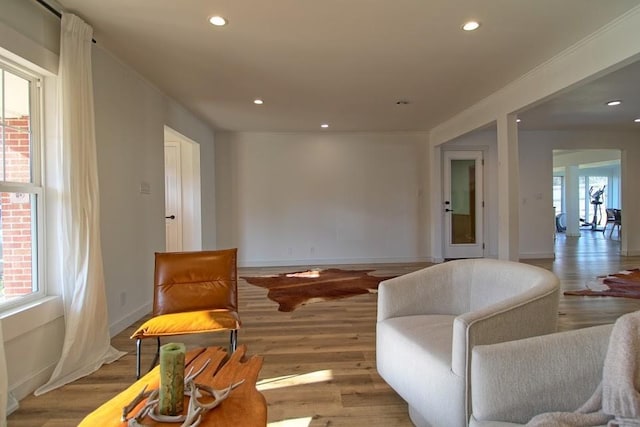 sitting room with a wealth of natural light, crown molding, and light hardwood / wood-style floors