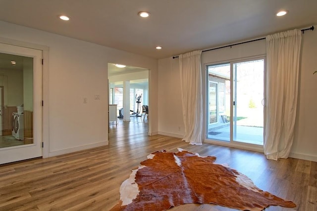 unfurnished room featuring washer / clothes dryer and light hardwood / wood-style floors