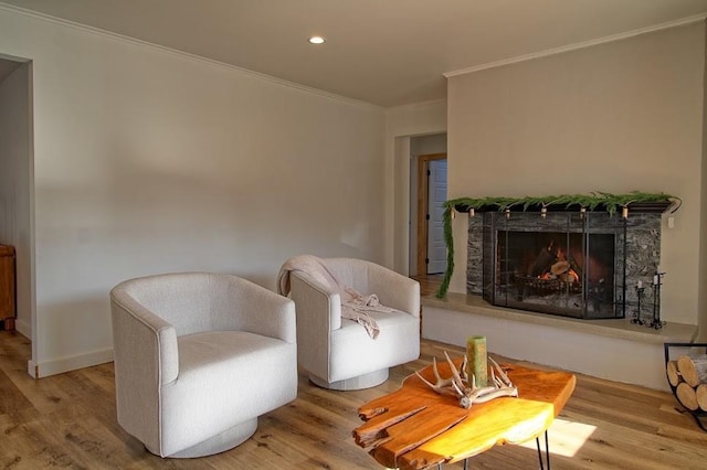 living area featuring a stone fireplace, wood-type flooring, and ornamental molding